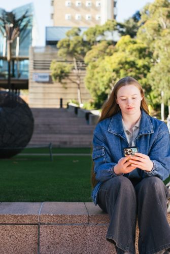 Student sitting by main walking using their phone