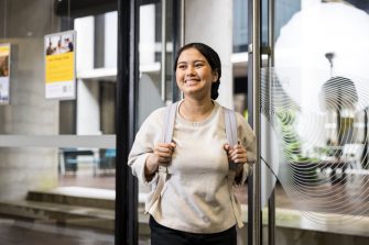 Student walking through door smiling at Student Services Student walking through door smiling at Student Services