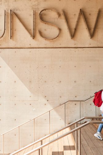 Students walking down L5 stairs in front of UNSW logo