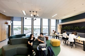 Students talking and studying in common room with bubble tea and laptops