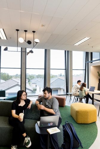 Students talking and studying in common room with bubble tea and laptops