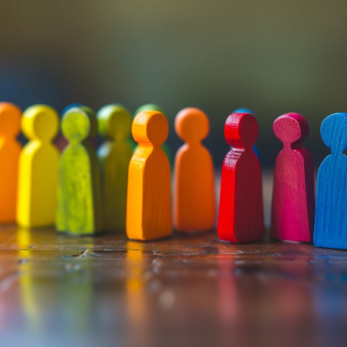 Small wooden figurines in different colors on a table to simulate a crowd of people Small wooden figurines in different colors on a table to simulate a crowd of people