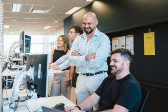 A group of adults working on computers, some are standing