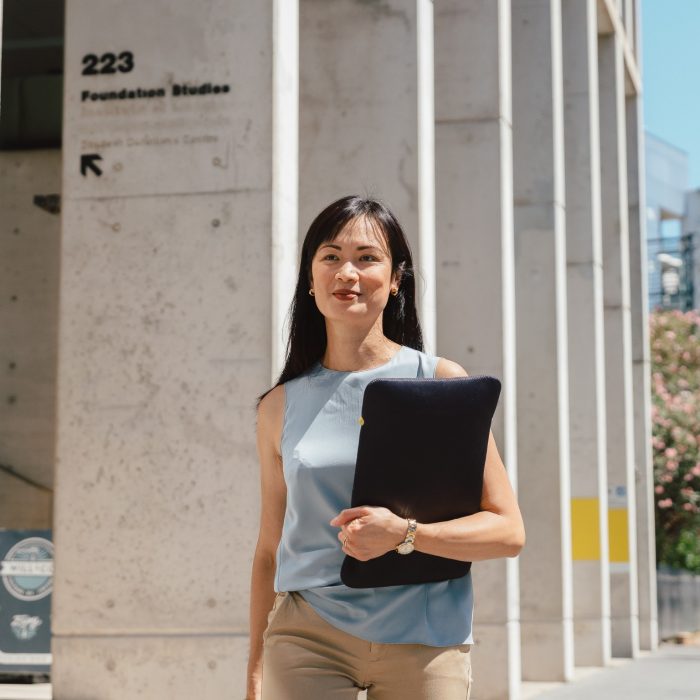 Woman walking outside UNSW College, holding a bag