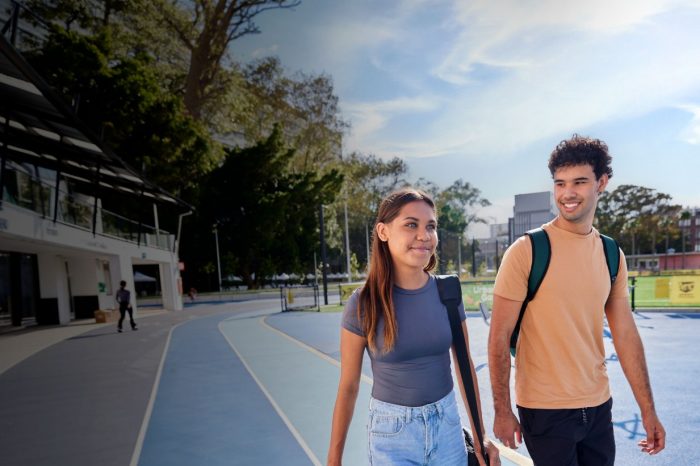 Two students walking on main campus near sport field