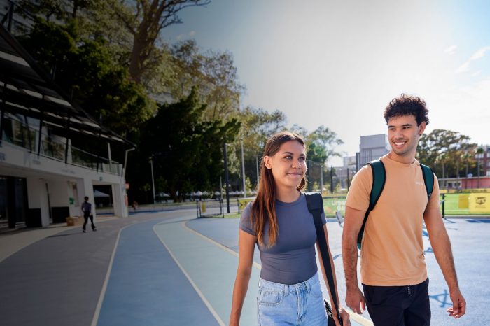 Two students walking on main campus near sport field
