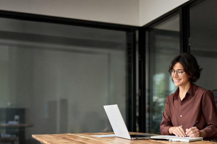 Professional woman at desk with laptop and notepad