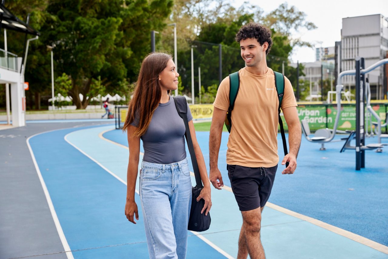 Two students smiling and walking in sports area