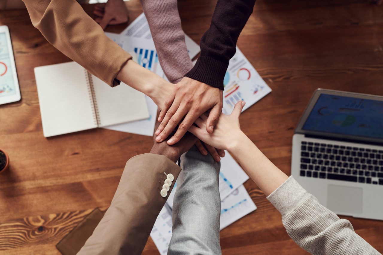 Six hands joining together over a desk