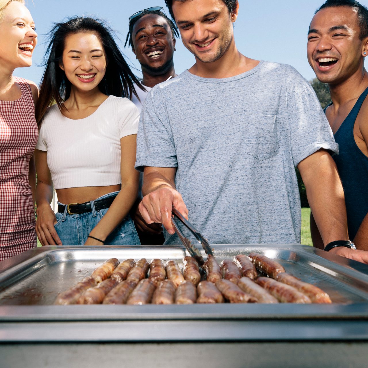 Students having BBQ at the beach cooking sausages