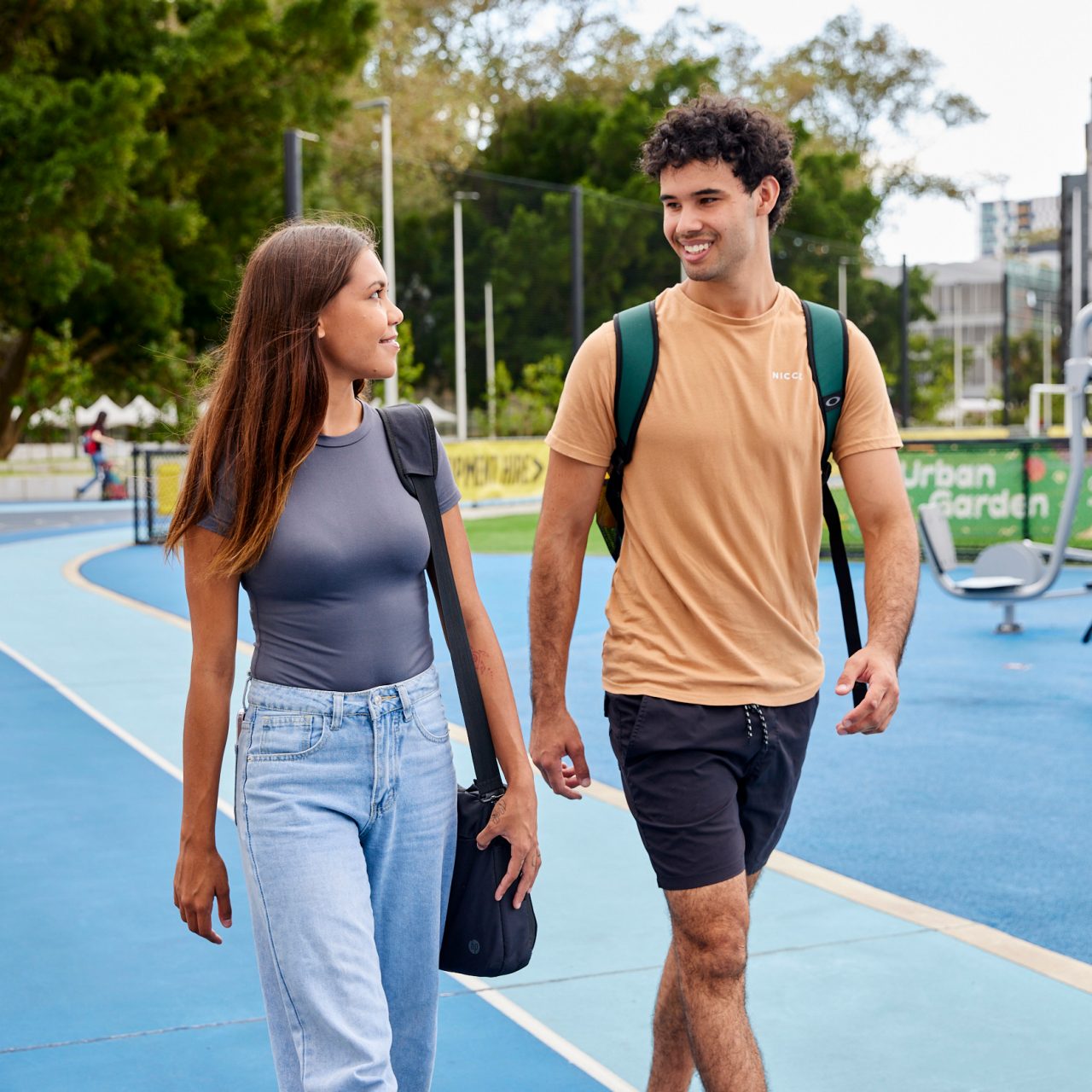 Two students smiling and walking in sports area