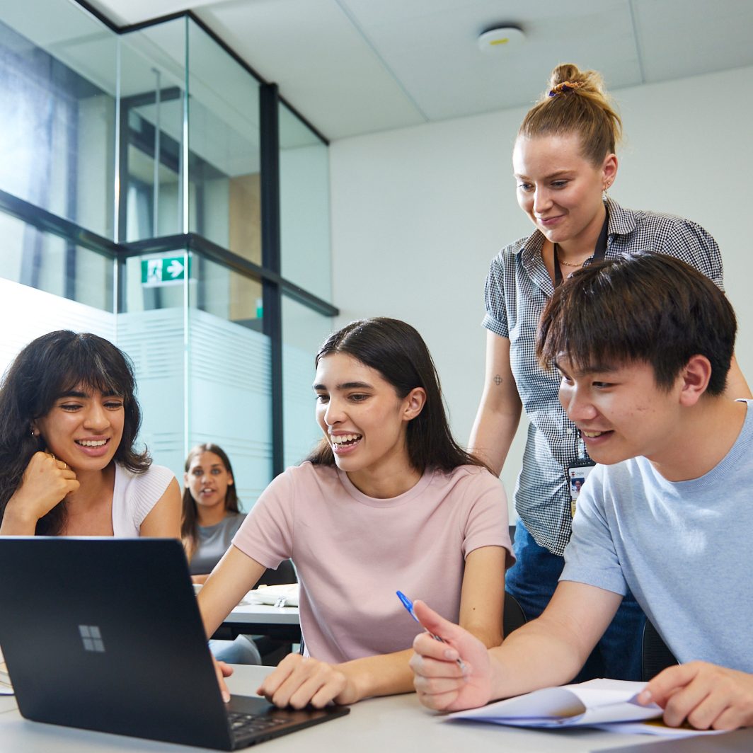 UNSW College Students in classroom, working on laptops, teacher supervises and educates
