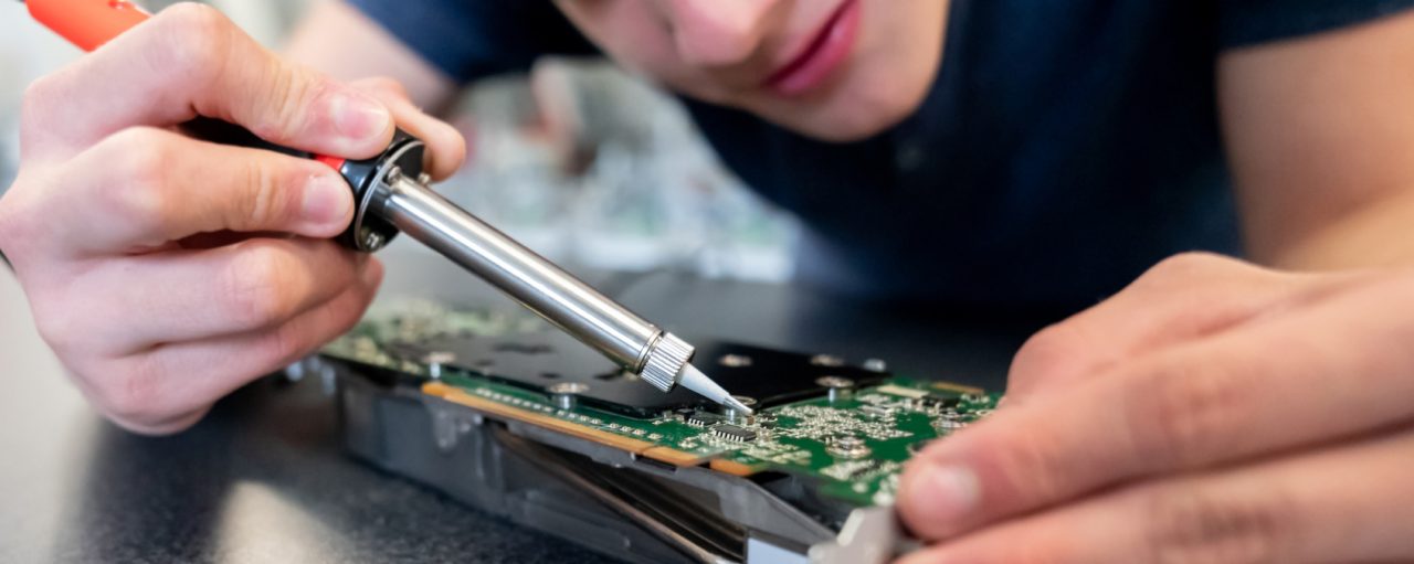 Close-up on an engineering student working on a robot and welding circuits