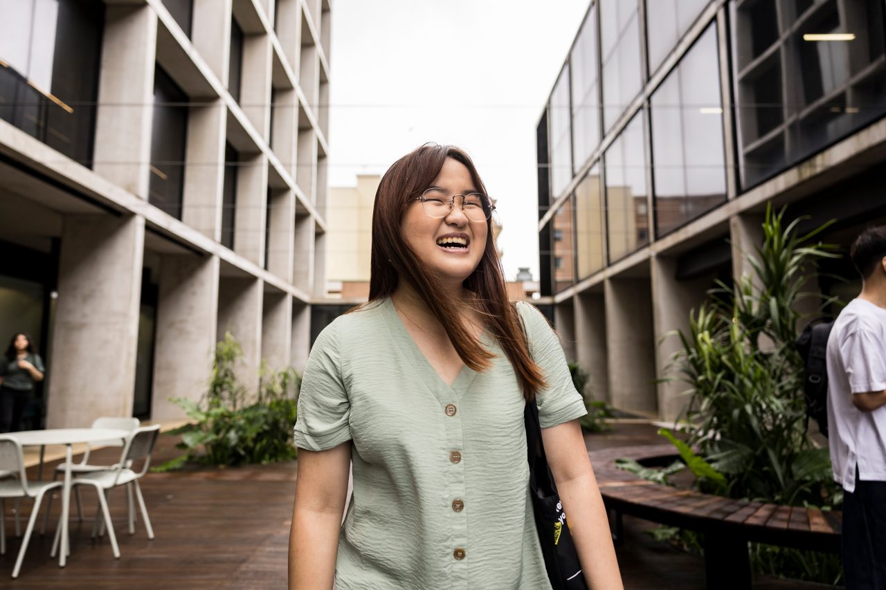 Female student laughing in courtyard at L5