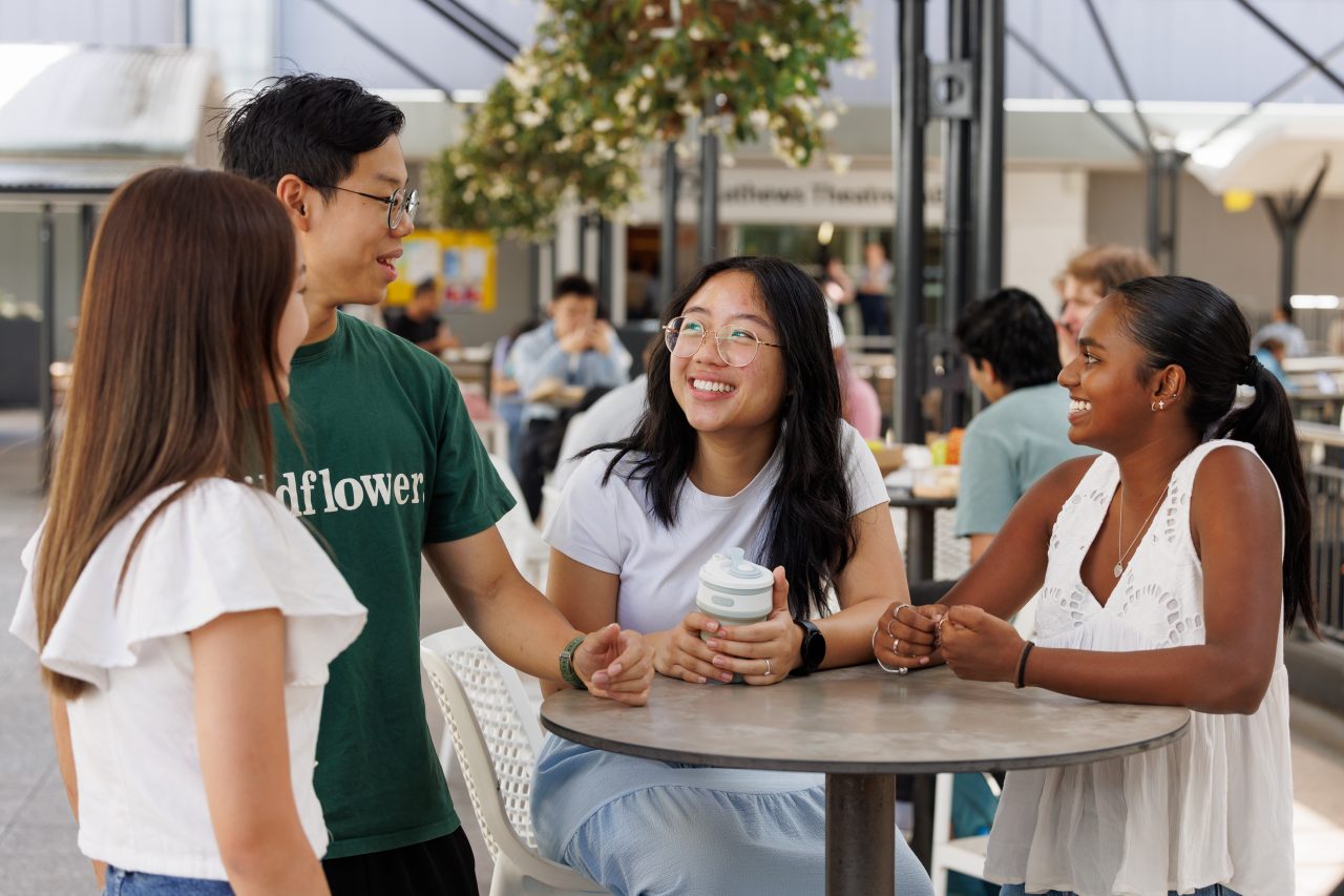 Three women laughing while sitting at a table with laptops