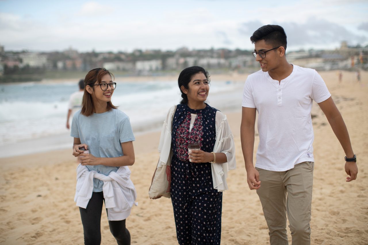 Students walking in sand at Bondi beach