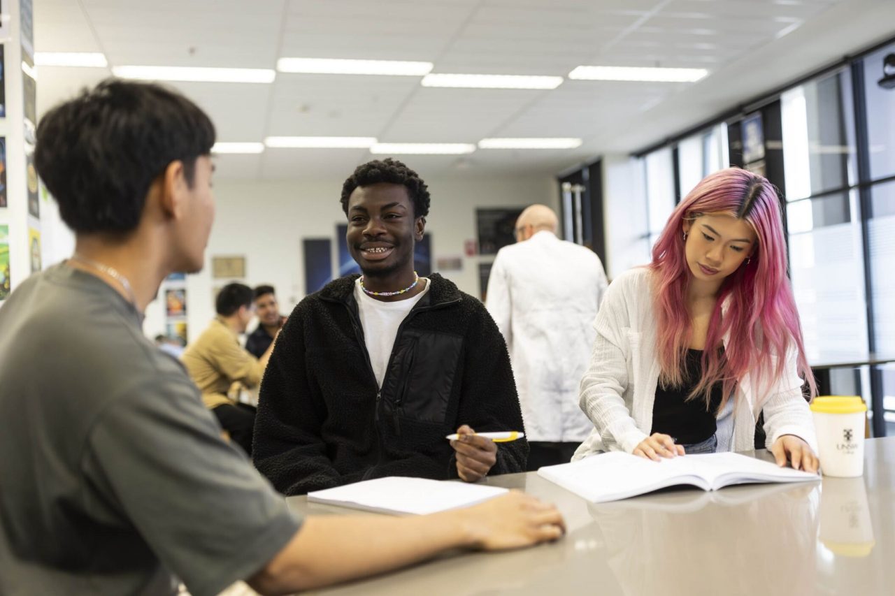 3 young students in class with open books